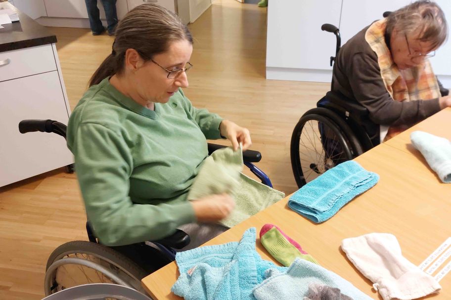 Zwei Klientinnen legen frisch gewaschene Hangerln zusammen.