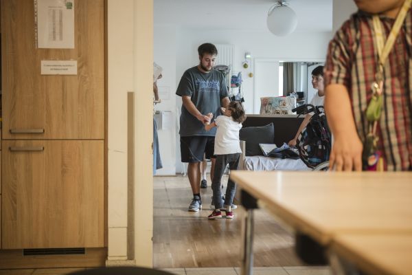 Eine Klientin macht im Wohnzimmer ihre Übungen mit den Betreuern