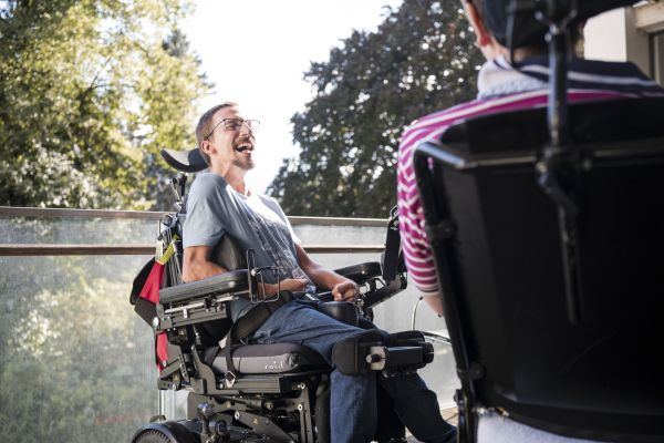 Zwei Klienten sitzen in ihren Rollstühlen auf der Terasse und Unterhalten sich