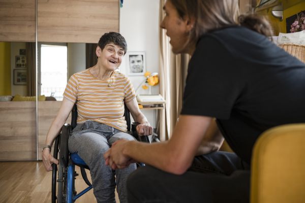 Eine Frau im Rollstuhl im Gespräch mit anderen Bewohnern und Mitarbeitern