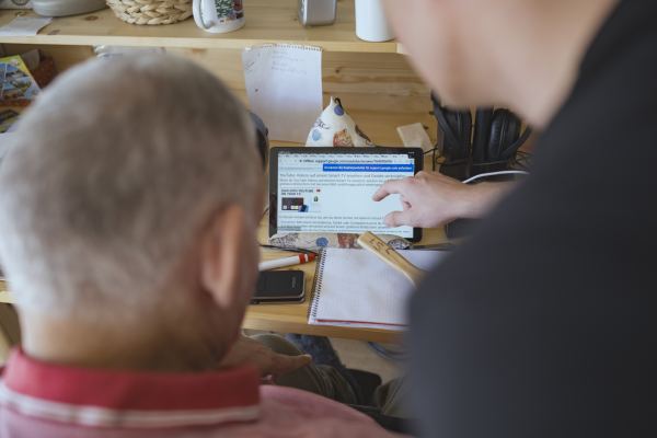 zwei Männer bedienen an einem Schreibtisch ein Tablet