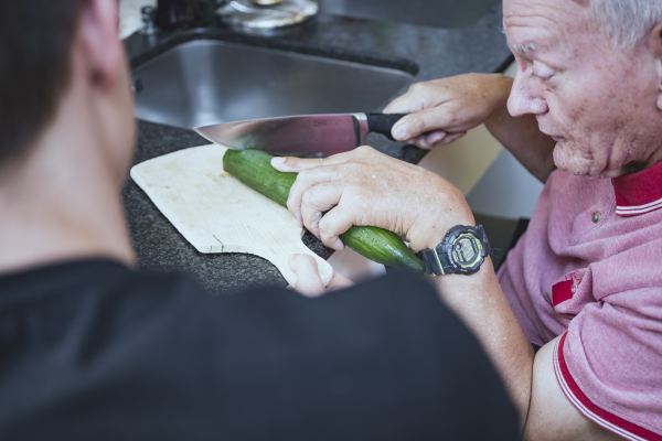 ein Mann schneidet auf einem Brett eine Salatgurke